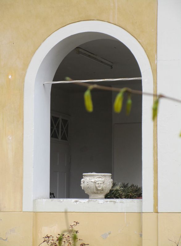Das weiße Bogenfenster ohne Glas mit der beigen Schale mit vier gleichen Gesichtern