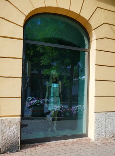 Die Schaufensterpuppe im Kleid mit großen silbernen Pailletten im blauen Bogenschaufenster